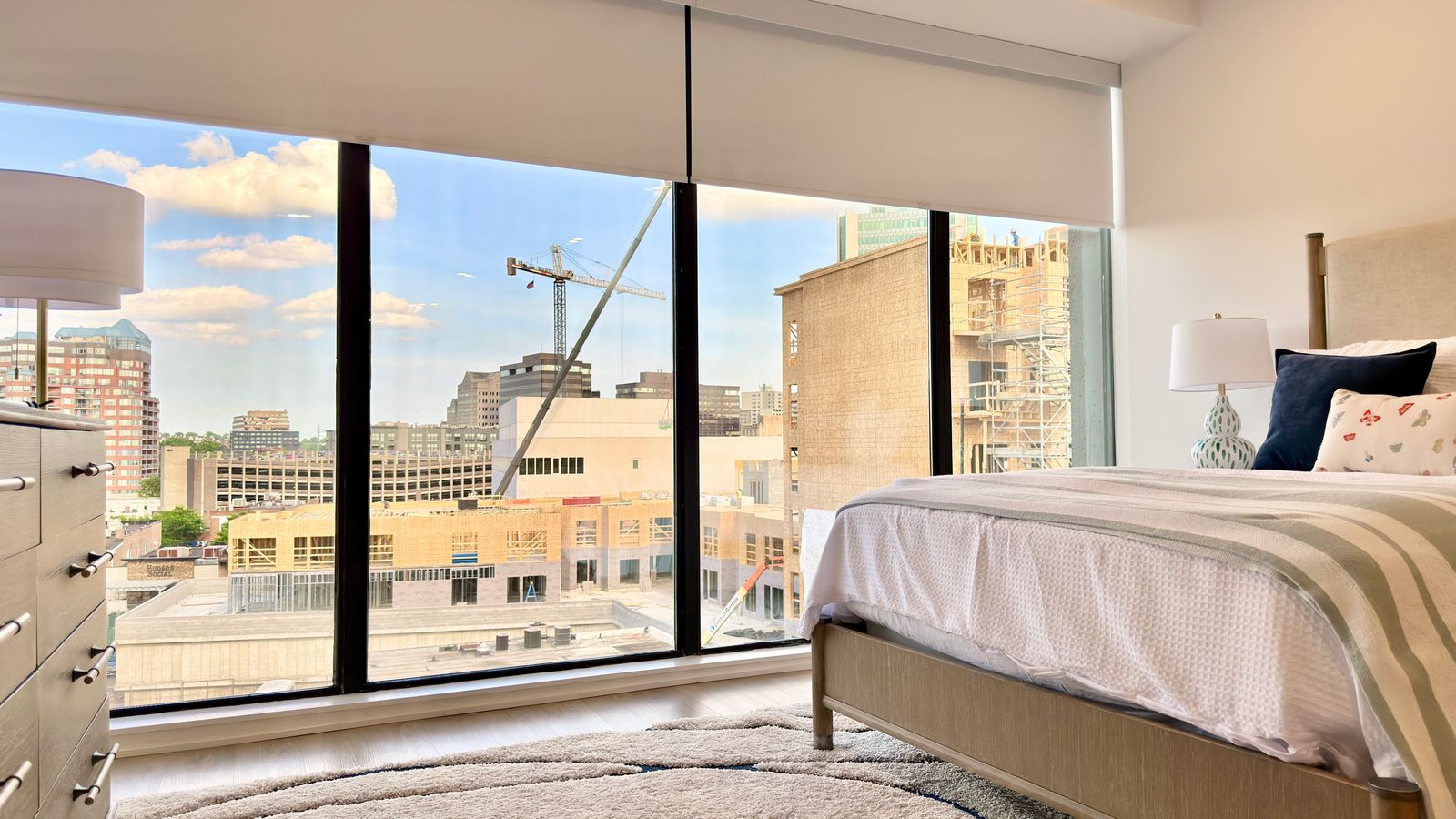 Staged bedroom in a downtown Stamford condo with floor-to-ceiling windows overlooking new construction
