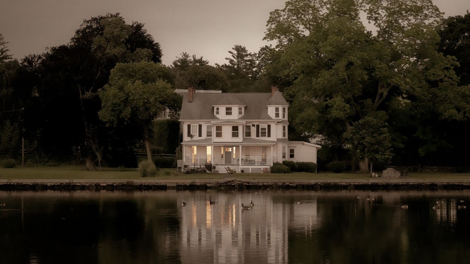 New England colonial home beside a pond, representative of Belltown, Stamford CT